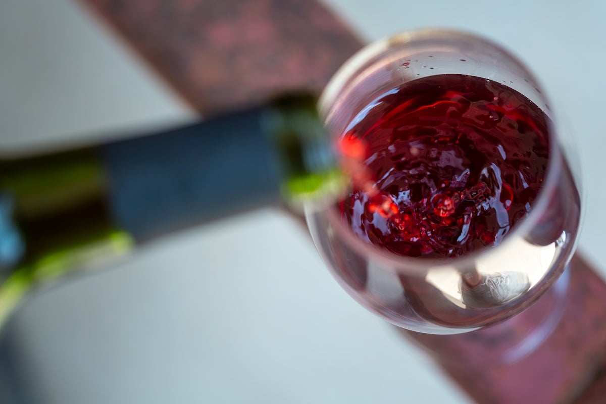 a glass of red wine with a bottle of wine in the background