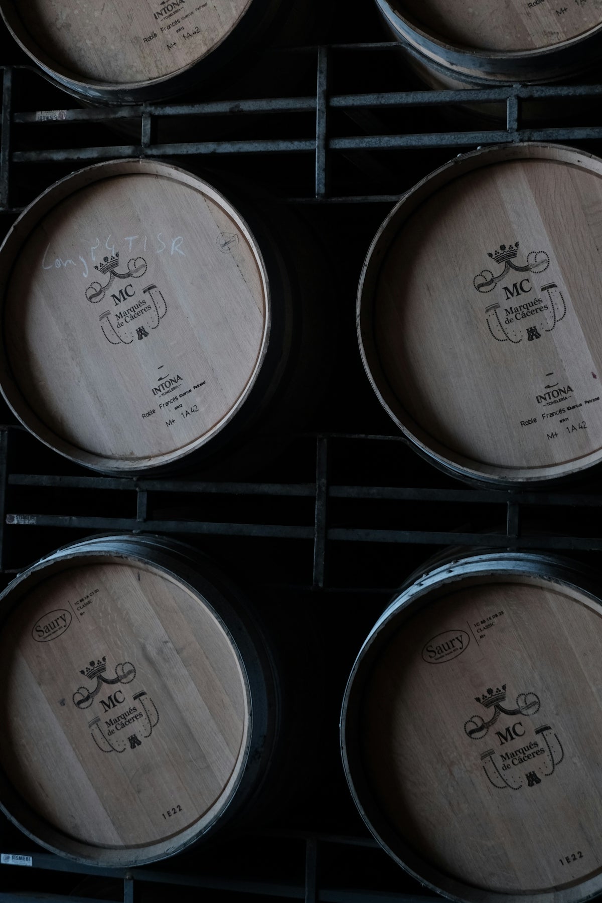 Wooden barrels stacked in a dark cellar.
